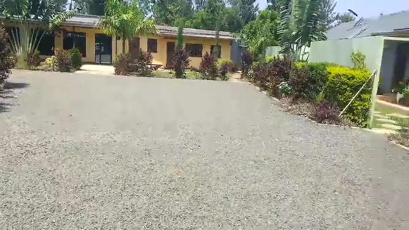 Gravel parking area inside the compound, with the main building and gardens behind