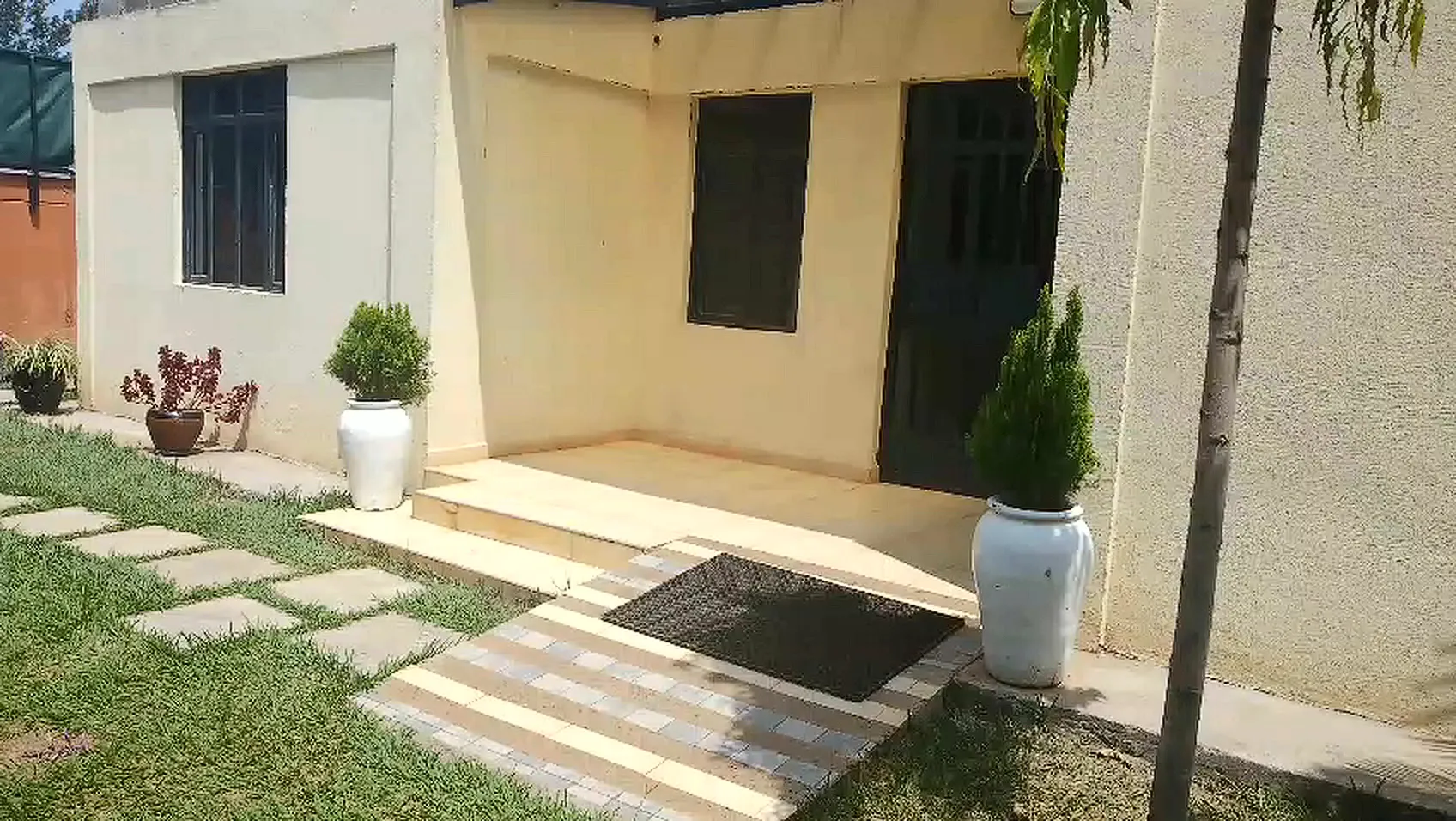 Entrance of the second guest block with potted plants and a stepping-stone path